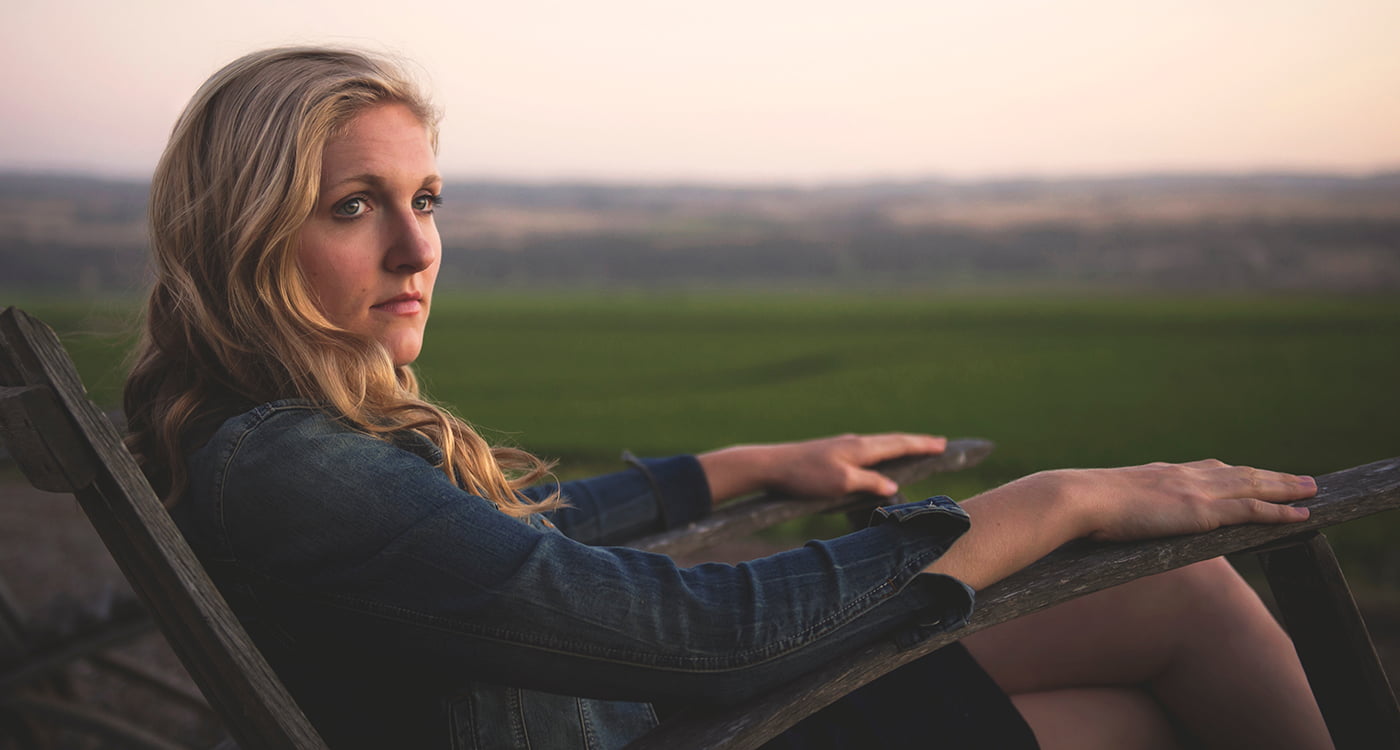 a woman sitting outside on a wooden chair